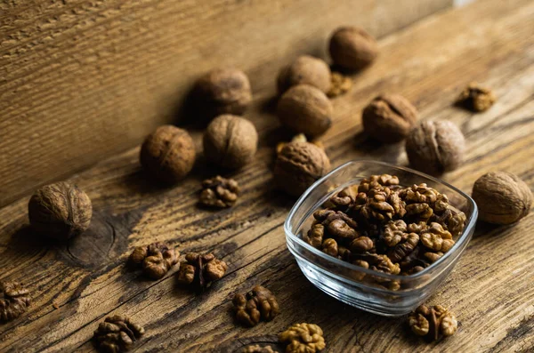 Noz em uma chapa fedorenta com nozes descascadas espalhadas e porca inteira que está em uma mesa vintage de madeira. Nozes é uma proteína vegetariana saudável alimento nutritivo. Noz em madeira velha rústica. — Fotografia de Stock