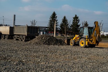 UKRAINE, LUTSK - 10 Nisan 2020: İnşaat alanında çakıllı çalışan sarı tekerlek yükleme makinesi. Asfaltlama için temel hazırlıklar yapılıyor. Yol inşaatı.