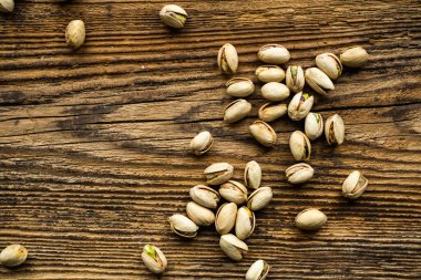 Ahşap şarap masasına saçılmış fıstıklar. Pistachio sağlıklı bir vejetaryen protein yiyeceğidir. Köhne odunlarda fıstıklar.
