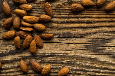 Bademler ahşap şarap masasına saçılmış. Uzayı kopyala Badem sağlıklı bir vejetaryen protein yiyeceğidir. Kırsal kesimlerdeki bademler.