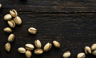 Ahşap şarap masasına saçılmış fıstıklar. Pistachio sağlıklı bir vejetaryen protein yiyeceğidir. Köhne odunlarda fıstıklar.