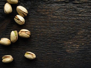 Ahşap şarap masasına saçılmış fıstıklar. Pistachio sağlıklı bir vejetaryen protein yiyeceğidir. Köhne odunlarda fıstıklar.