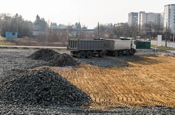 A dump truck is dumping gravel on a construction site. Dump truck dumps its load of gravel on a new road construction project. Road building. Preparing of the fundament for a asphalting.