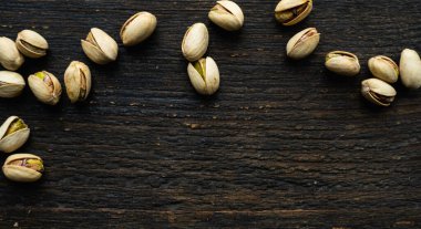 Ahşap şarap masasına saçılmış fıstıklar. Pistachio sağlıklı bir vejetaryen protein yiyeceğidir. Köhne odunlarda fıstıklar.