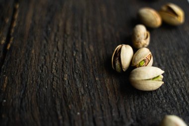 Ahşap şarap masasına saçılmış fıstıklar. Pistachio sağlıklı bir vejetaryen protein yiyeceğidir. Köhne odunlarda fıstıklar.