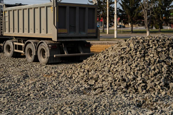 A dump truck is dumping gravel on a construction site. Dump truck dumps its load of gravel on a new road construction project. Road building. Preparing of the fundament for a asphalting.