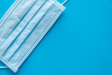 Mavi arka planda tıbbi koruyucu maske var. Koronavirüsü önlemek için ağzı ve burnu kapamak için 3 katlı tıbbi maske. Bakterilerin prosedür maskesi. Coronavirus karantinası.
