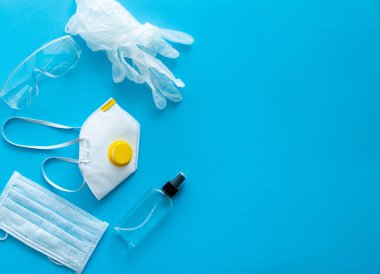 Tıbbi koruyucu maske, solunum cihazı ffp, sabun, lastik eldivenler, antiseptik ve koruyucu gözlükler mavi arka planda yatar. Covid-19 'a karşı anti-virüs koruma kiti. Coronavirus salgını 2019.