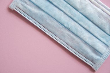 Mavi tıbbi koruyucu maske pembe arka planda izole edilmiş. Koronavirüsü önlemek için ağzı ve burnu kapamak için 3 katlı tıbbi maske. Bakterilerin prosedür maskesi. Coronavirus karantinası.