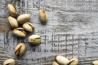Ahşap şarap masasına saçılmış fıstıklar. Pistachio sağlıklı bir vejetaryen protein yiyeceğidir. Köhne odunlarda fıstıklar.