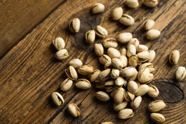 Ahşap şarap masasına saçılmış fıstıklar. Pistachio sağlıklı bir vejetaryen protein yiyeceğidir. Köhne odunlarda fıstıklar.