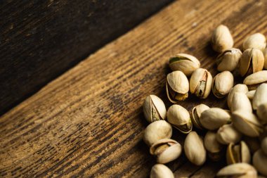 Ahşap şarap masasına saçılmış fıstıklar. Pistachio sağlıklı bir vejetaryen protein yiyeceğidir. Köhne odunlarda fıstıklar.