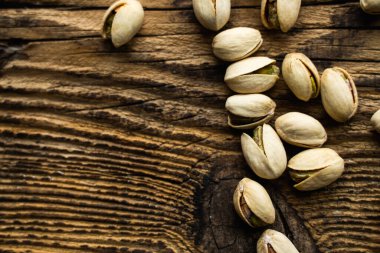 Ahşap şarap masasına saçılmış fıstıklar. Pistachio sağlıklı bir vejetaryen protein yiyeceğidir. Köhne odunlarda fıstıklar.