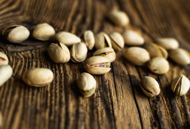 Ahşap şarap masasına saçılmış fıstıklar. Pistachio sağlıklı bir vejetaryen protein yiyeceğidir. Köhne odunlarda fıstıklar.