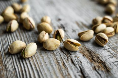 Ahşap şarap masasına saçılmış fıstıklar. Pistachio sağlıklı bir vejetaryen protein yiyeceğidir. Köhne odunlarda fıstıklar.