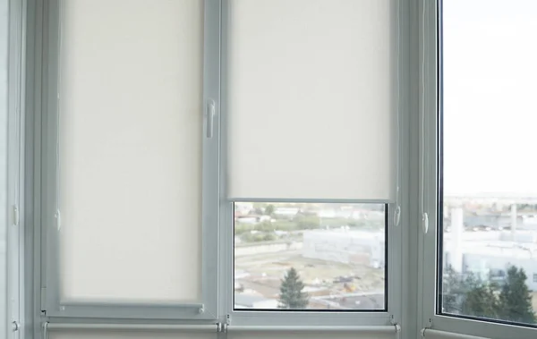 Detalles de persianas enrollables de tela blanca en la ventana de plástico con textura de madera en la sala de estar . —  Fotos de Stock