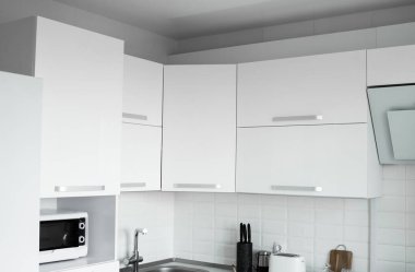 Konforlu bir mutfağın üzerinde beyaz, yaldızlı mutfak cepheleri. Modern beyaz mutfak temiz iç tasarım.