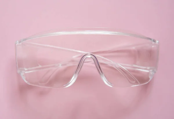 Protective glasses lying on a pink background.