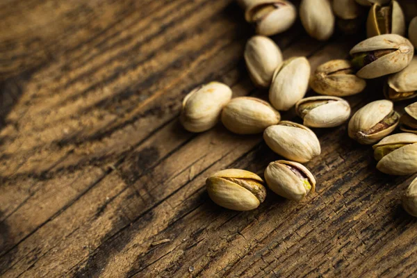 Pistazien verstreut auf dem hölzernen Vintagetisch. Pistazie ist eine gesunde vegetarische Proteinnahrung. Pistazien auf rustikalem altem Holz. — Stockfoto