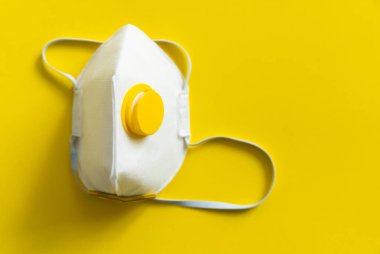 Solunum maskesi ya da toz maskesi ağız ve burun için sarı arka planda izole edilmiş koronavirüsü önler. Hava kirliliği, grip ve koronavirüsten korunma.