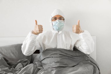 2019 'un sonundaki koronavirüs karantinasının sona ermesini bekleyen koruyucu beyaz takım elbiseli ve yüz maskeli bir adamın portresi. Kişisel tecrit.