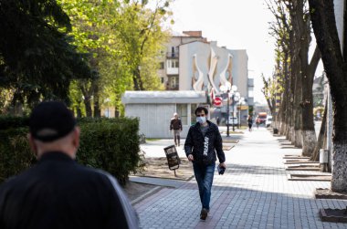 UKRAINE, KYIV - 25 Nisan 2020: Sokaklarda yürüyen adam Corona virüsü veya Covid 19 salgınını önlemek için tıbbi maske takıyor.
