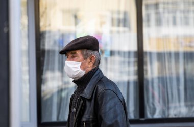 UKRAINE, KYIV - 25 Nisan 2020: Sokaklarda yürüyen adam Corona virüsü veya Covid 19 salgınını önlemek için tıbbi maske takıyor.
