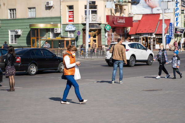 UKRAINE, KYIV - April 25, 2020: Woman wearing a medical mask to prevent of bacterial infection Corona virus or Covid 19 epidemic walking on the street.