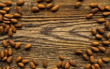 Bademler, ortada fotokopi alanı olan ahşap vintage masaya saçılmış. Badem sağlıklı bir vejetaryen protein yiyeceğidir. Kırsal kesimlerdeki bademler.