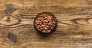 Eski ahşap bir masada, arka planda fotokopi alanı olan küçük bir tabakta yer fıstığı. Fıstık ezmesi sağlıklı bir vejetaryen proteindir..