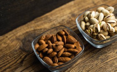 Badem, ahşap bir masada duran küçük bir tabakta fıstık. Fındık sağlıklı bir vejetaryen protein ve besleyici yemektir. Taşralı eski odunlarda fındıklar.