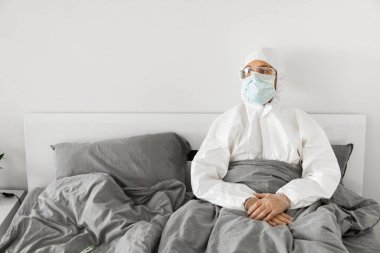 2019 'un sonundaki koronavirüs karantinasının sona ermesini bekleyen koruyucu beyaz takım elbiseli ve yüz maskeli bir adamın portresi. Kişisel tecrit.