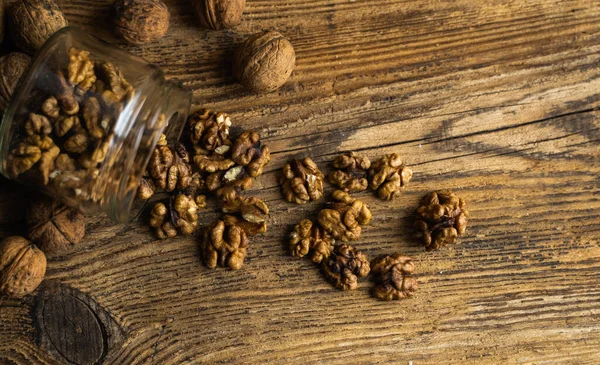 Noz espalhada na mesa vintage a partir de um jarro whith uma nozes inteiras. A noz é uma proteína vegetariana saudável alimento nutritivo. Grânulos de nozes e nozes inteiras em madeira velha rústica . — Fotografia de Stock