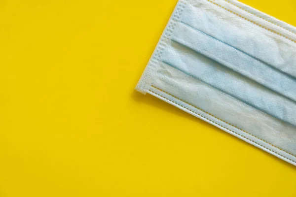 Kék orvosi védőmaszk sárga alapon. Eldobható 3 rétegű orvosi maszk, hogy fedezze a száj és az orr, hogy megakadályozzák a koronavírus. Eljárási maszk baktériumokból. Koronavírus-karantén. — Stock Fotó