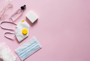 Tıbbi koruyucu maske, solunum cihazı ffp, sabun, lastik eldivenler, antiseptik ve koruyucu gözlükler pembe arka planda yatar. Covid-19 'a karşı anti-virüs koruma kiti. Coronavirus salgını 2019.