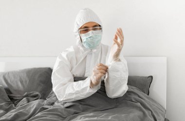 2019 'un sonundaki koronavirüs karantinasının sona ermesini bekleyen koruyucu beyaz takım elbiseli ve yüz maskeli bir adamın portresi. Kişisel tecrit.