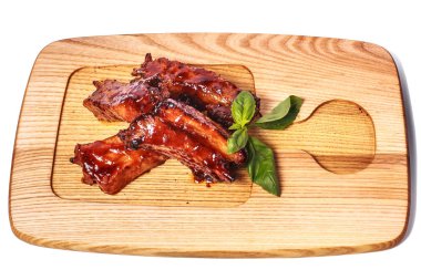     Barbekü ızgara pirzola ve ahşap tabakta yeşil fesleğen. Üst Manzara. Beyazda izole edilmiş