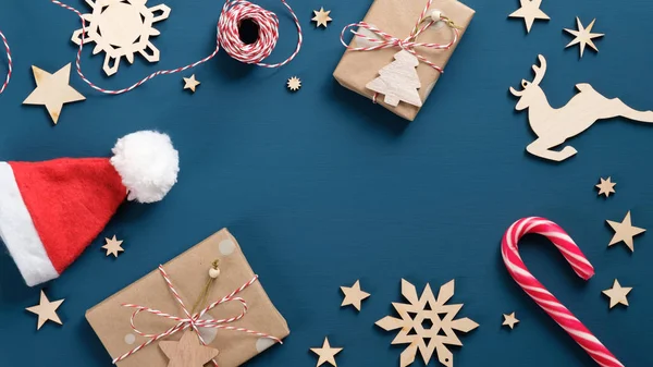 Quadro de decorações de férias de Natal. Top view caixas de presente papel kraft embrulhado, cana-de-açúcar, elementos de madeira vintage Xmas, chapéu de Ano Novo, corda listrada. Mockup de banner de Natal, modelo de cartão postal . — Fotografia de Stock