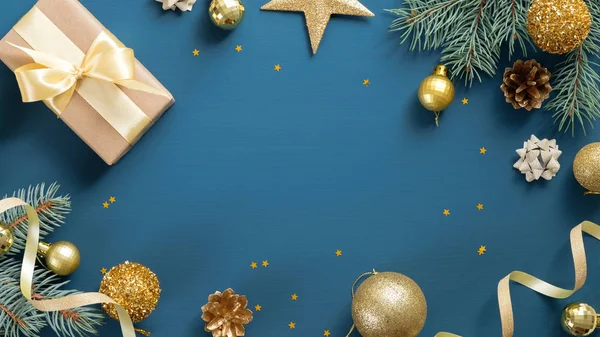 İçinde çam ağacı dalları, hediyeler, mavi arka planda altın süslemeler olan Noel kartı. Düz konum, üst görünüm, kopyalama alanı. Noel çerçevesi, yeni yıl afişi.