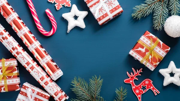 ギフトボックス、松の木の枝、紙の包装ロールと青の装飾を持つクリスマスの背景。クリスマス、冬の休日、新年のコンセプト. — ストック写真
