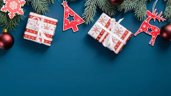전나무 가지가 달린 크리스마스 프레임, 붉은 나무 장식, 바우 블, 파란 배경의 선물 상자. 평면, 맨 위 뷰, 복사 공간. Xmas, winter holiday, New Year 컨셉트. — 스톡 사진
