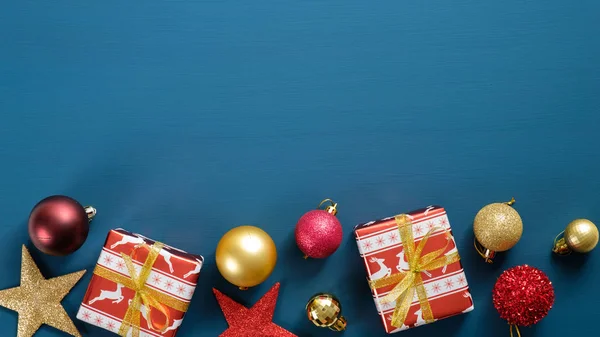 Borda moldura de Natal com decorações vermelhas e douradas no fundo azul. Top vista ornamentos de madeira, caixas de presente papel festivo embrulhado, estrelas, bolas. Modelo de cartão de saudação de Ano Novo moderno . — Fotografia de Stock