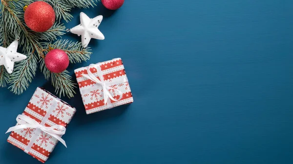 フラットは青の背景にヴィンテージクリスマスの装飾を置きます。松の木の枝、ギフトボックス、白い星、赤いボールを持つトップビュークリスマスカード。クリスマス、冬の休日、新年のコンセプト. — ストック写真