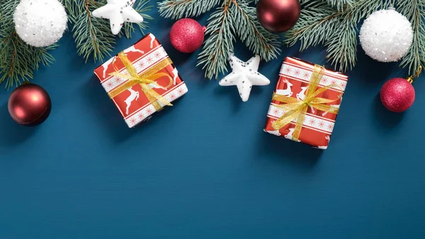 Presentes de Natal papel festivo embrulhado, bolas brancas e vermelhas, estrelas, ramos de pinheiros sobre fundo azul. Deitado plano, vista superior. Ano Novo modelo de cartão de saudação, Xmas cabeçalho banner mockup — Fotografia de Stock