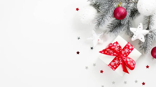 크리스마스 스타일을 최소화 한 배너는 Xmas 선물로 리본 리본 리본 리본, 전나무 가지, 하얀 배경에 콘 페티 별로 장식된 축제 장식 이 있다. 평면 배치, 상단 뷰, 복사 공간 — 스톡 사진