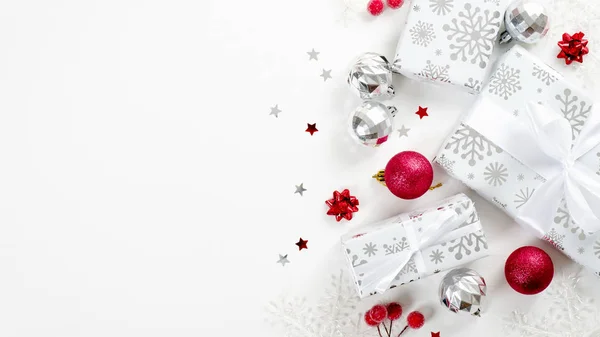Верхний вид рождественские подарки, красные и серебряные украшения на белом фоне с копировальным пространством. Плоские подарочные коробки с ленточками, мячами, конфетти. Рождество, зимние праздники, новогодняя концепция — стоковое фото