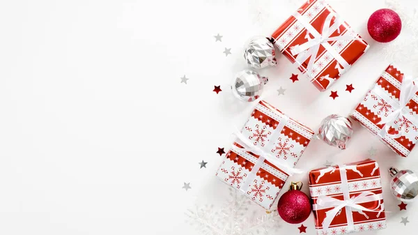 Χριστουγεννιάτικα κομψά δώρα με ασημί και κόκκινες διακοσμήσεις σε λευκό φόντο. Επίπεδο lay, πάνω όψη, αντιγραφή χώρου. Χειμερινές διακοπές, Χριστούγεννα, Πρωτοχρονιά έννοια — Φωτογραφία Αρχείου