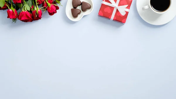 Κάρτα του Αγίου Βαλεντίνου. Top πλαίσιο συνόρων από τριαντάφυλλο λουλούδια, φλιτζάνι καφέ, κουτί δώρου τυλιγμένο κόκκινο χαρτί και γλυκό καραμέλα σε μπλε φόντο με χώρο αντίγραφο. Ρομαντικό καρτ ποστάλ. — Φωτογραφία Αρχείου