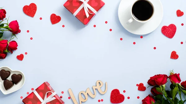 O cartão de Natal do dia dos namorados. Flat lay presentes, forma corações vermelhos, doces, xícara de café, flores de rosa, sinal de texto "Amor" no fundo azul. Fronteira de moldura romântica, maquete de cartão de saudação — Fotografia de Stock