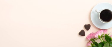 Kahve fincanı, güller, pastel bej arka planda kalp şeklinde şekerler. Sevgililer Günü, aşk, Anneler Günü konsepti. Düz konum, üst görünüm, kopyalama alanı.